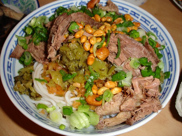A bowl of Guilin rice noodles with braised beef and peanuts