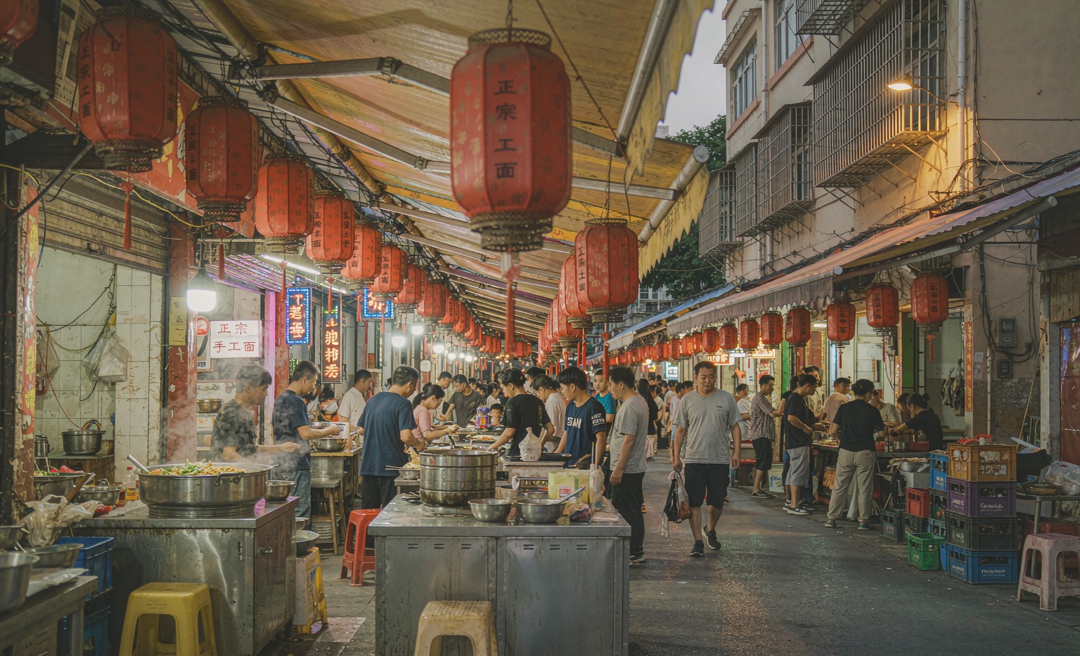 Red lanterns and steaming food stalls along a busy Chinese night market alley at dusk