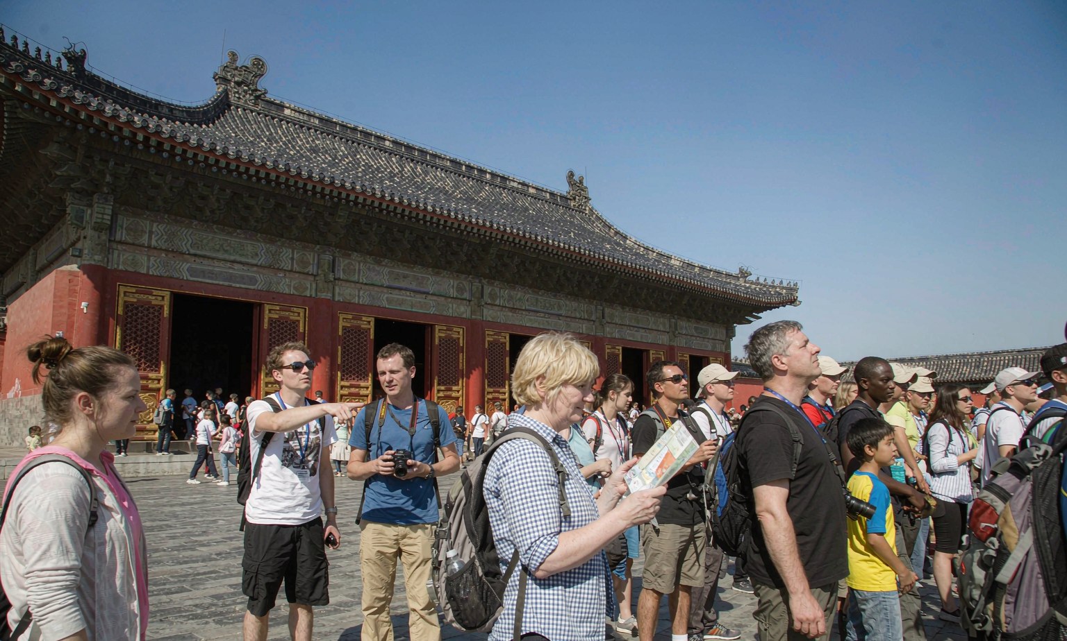 International visitors with backpacks and a map in front of a traditional Chinese gate tower