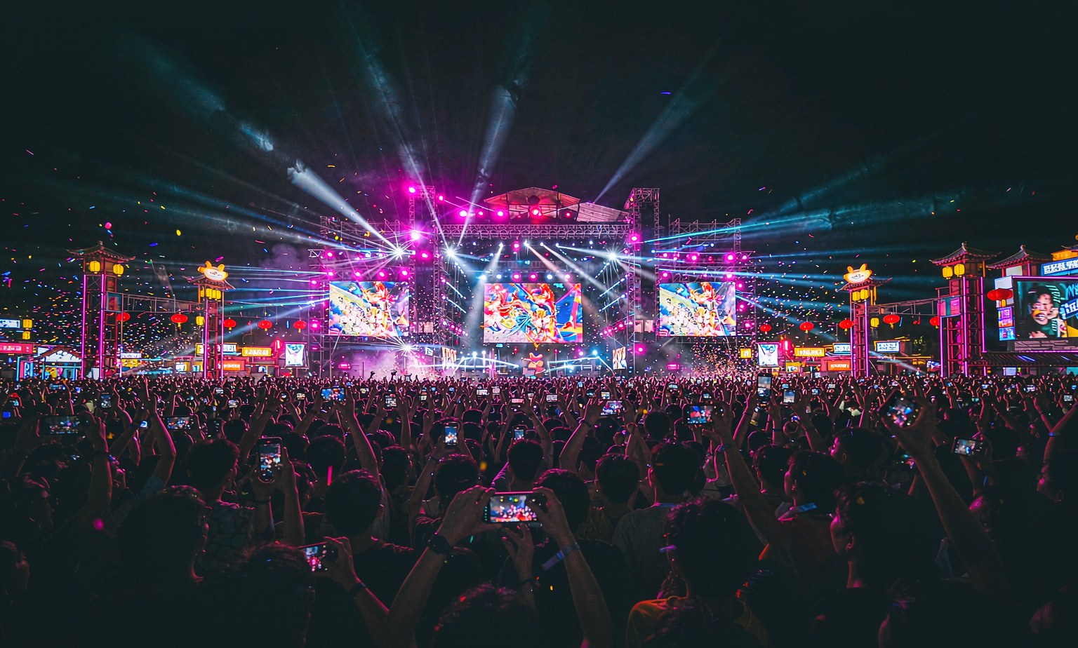 A large outdoor music festival at night in China, seen from behind the crowd