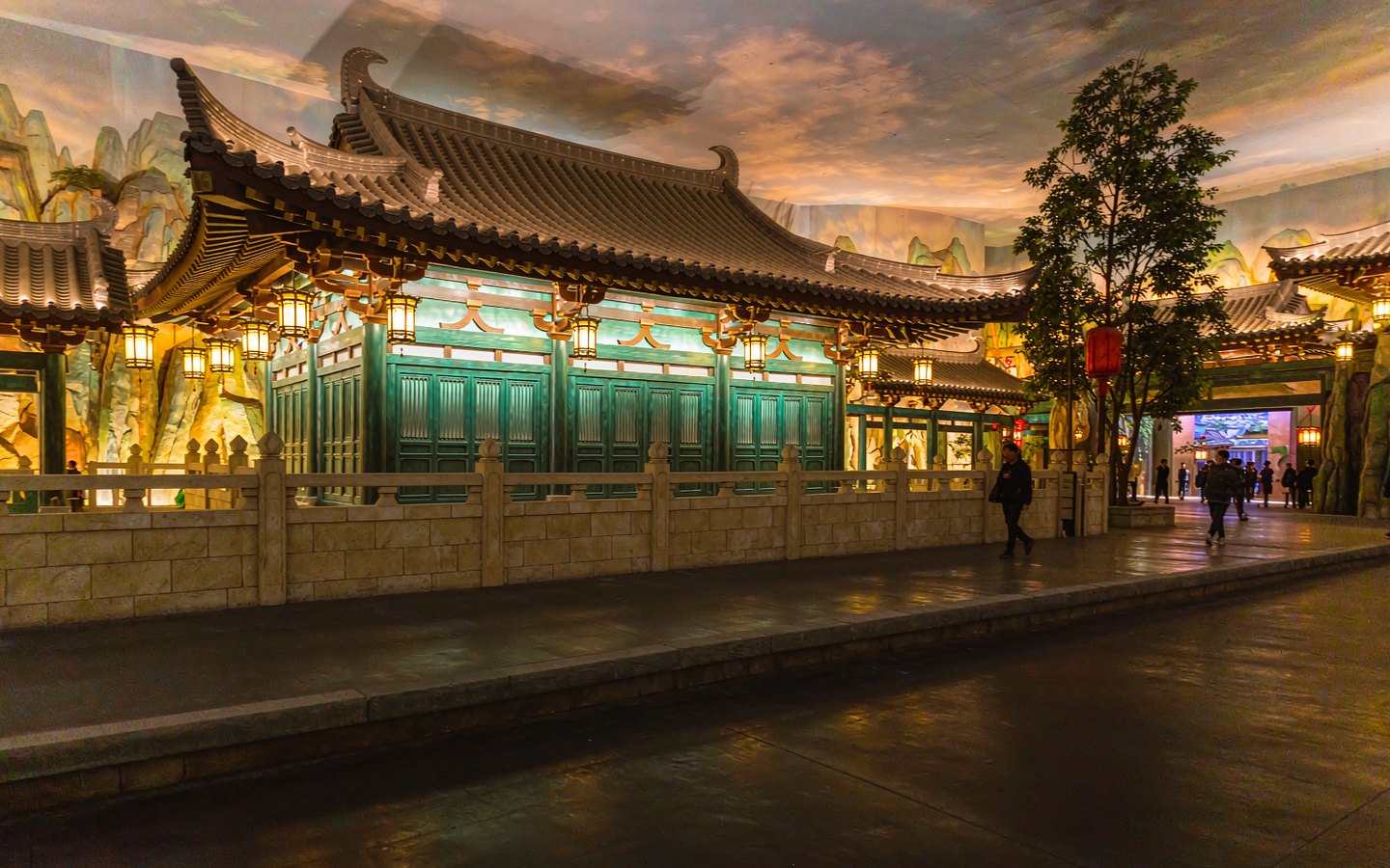 Lantern-lit Chinese fantasy village inside a theme park at dusk