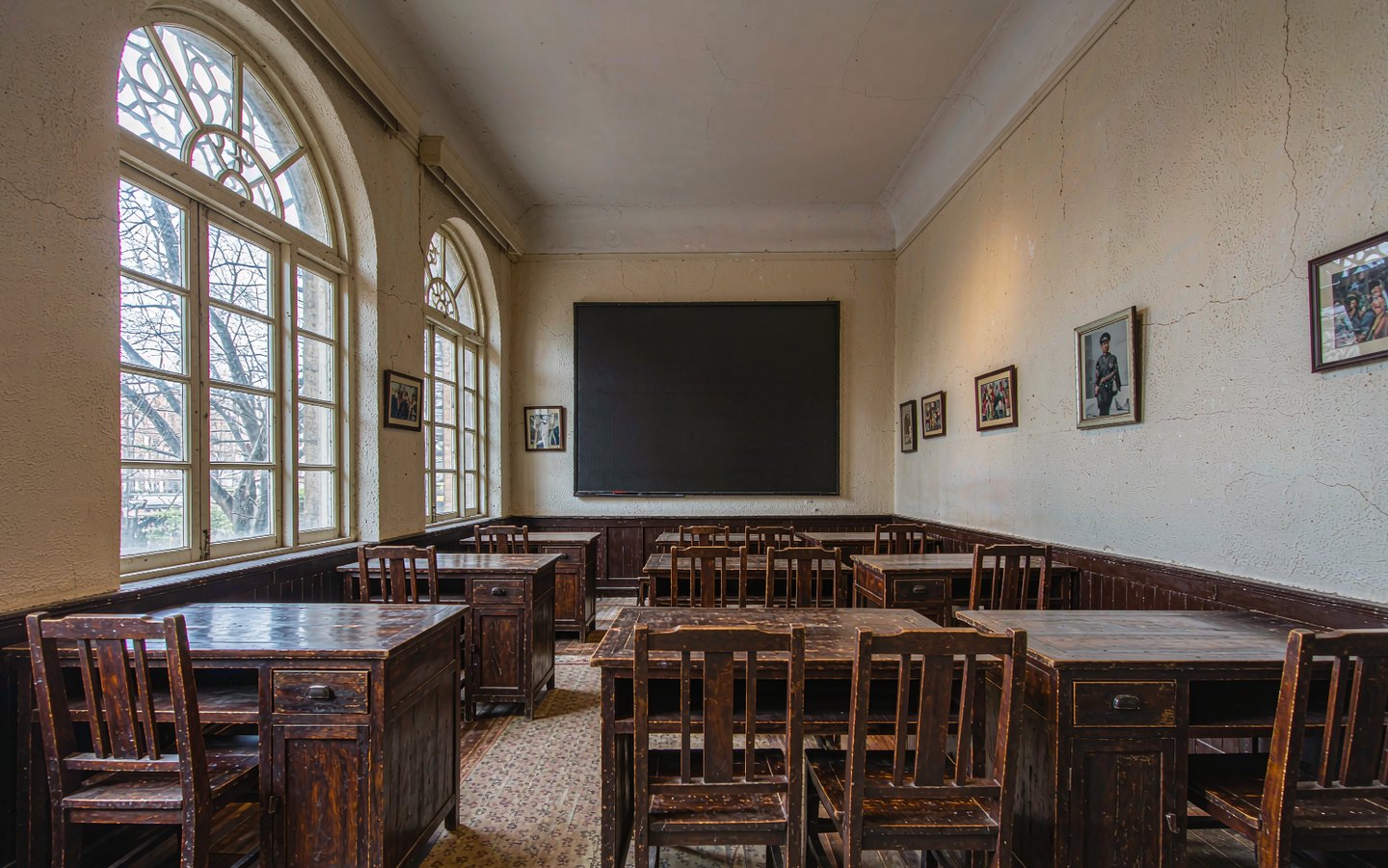 1910s classroom with dark wooden desks in an arched schoolhouse
