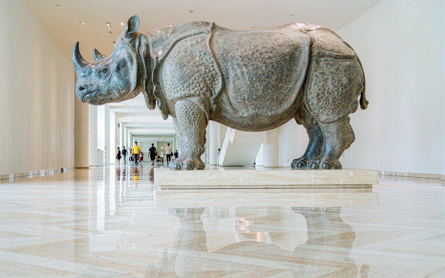 Massive carved stone rhinoceros in a bright museum hall