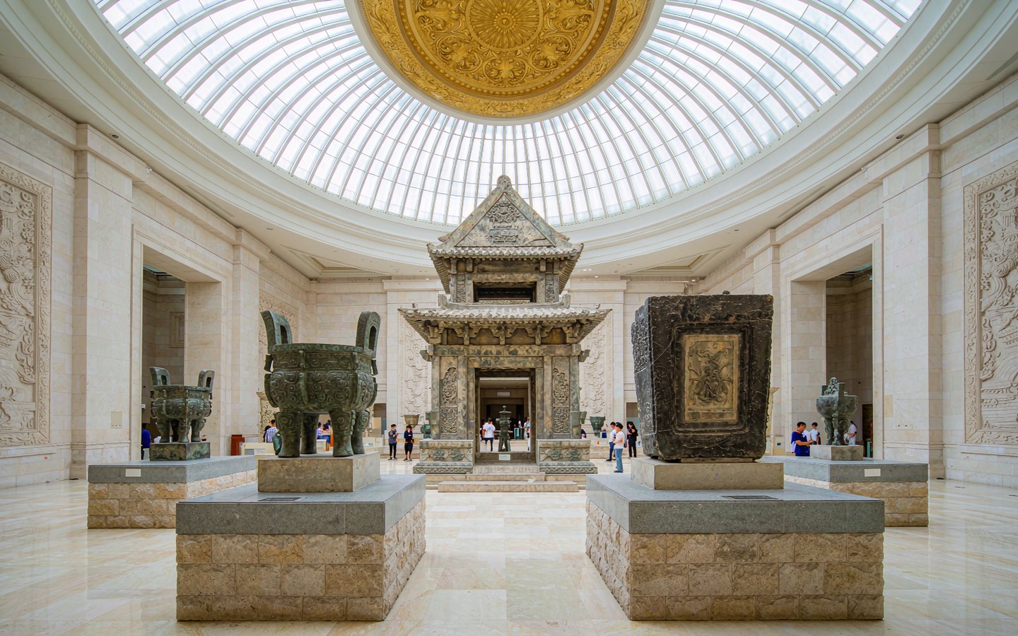 Grand museum atrium with ancient bronze vessels on pedestals