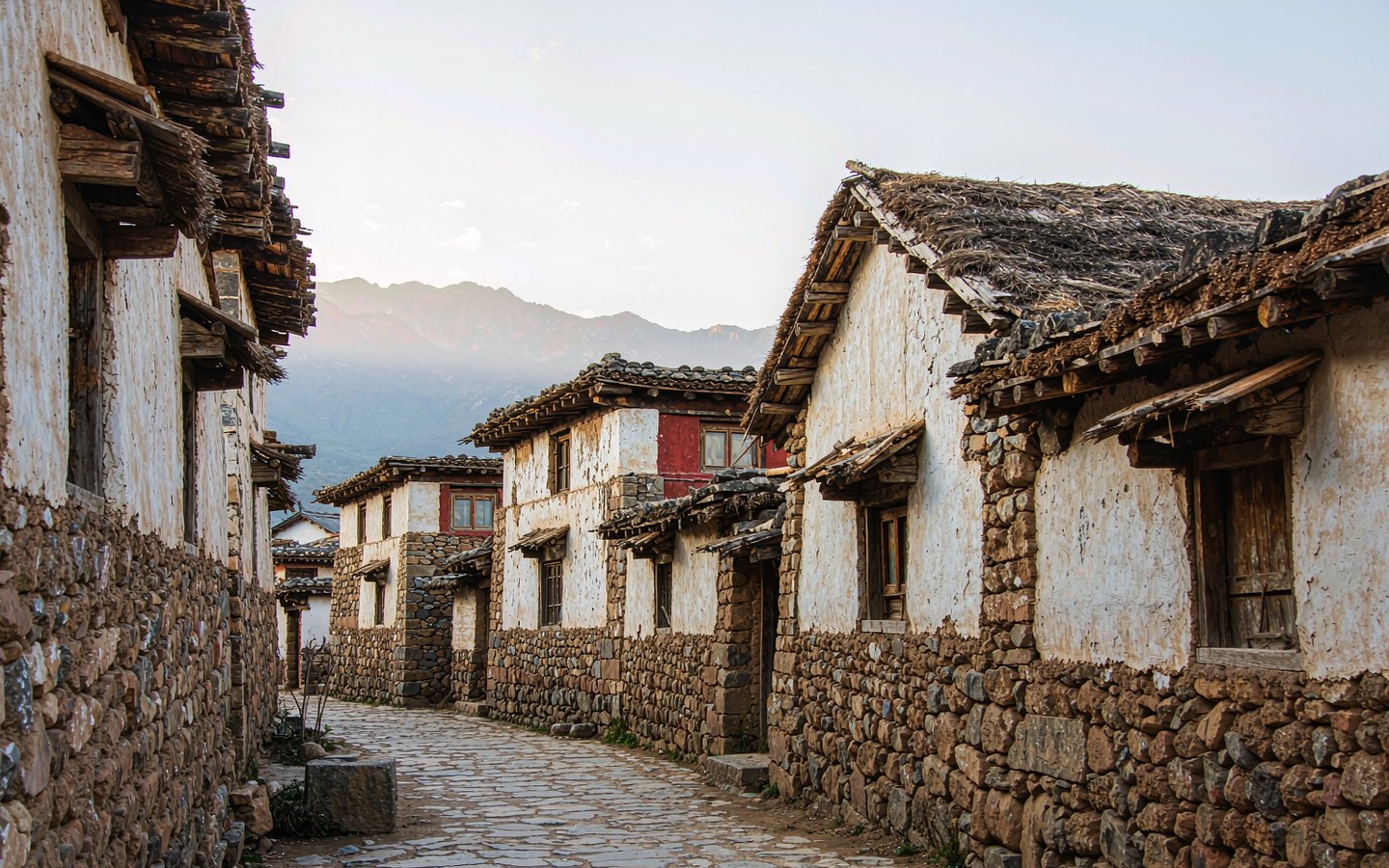 Flagstone horse-road lane between stone farmhouses under the mountains