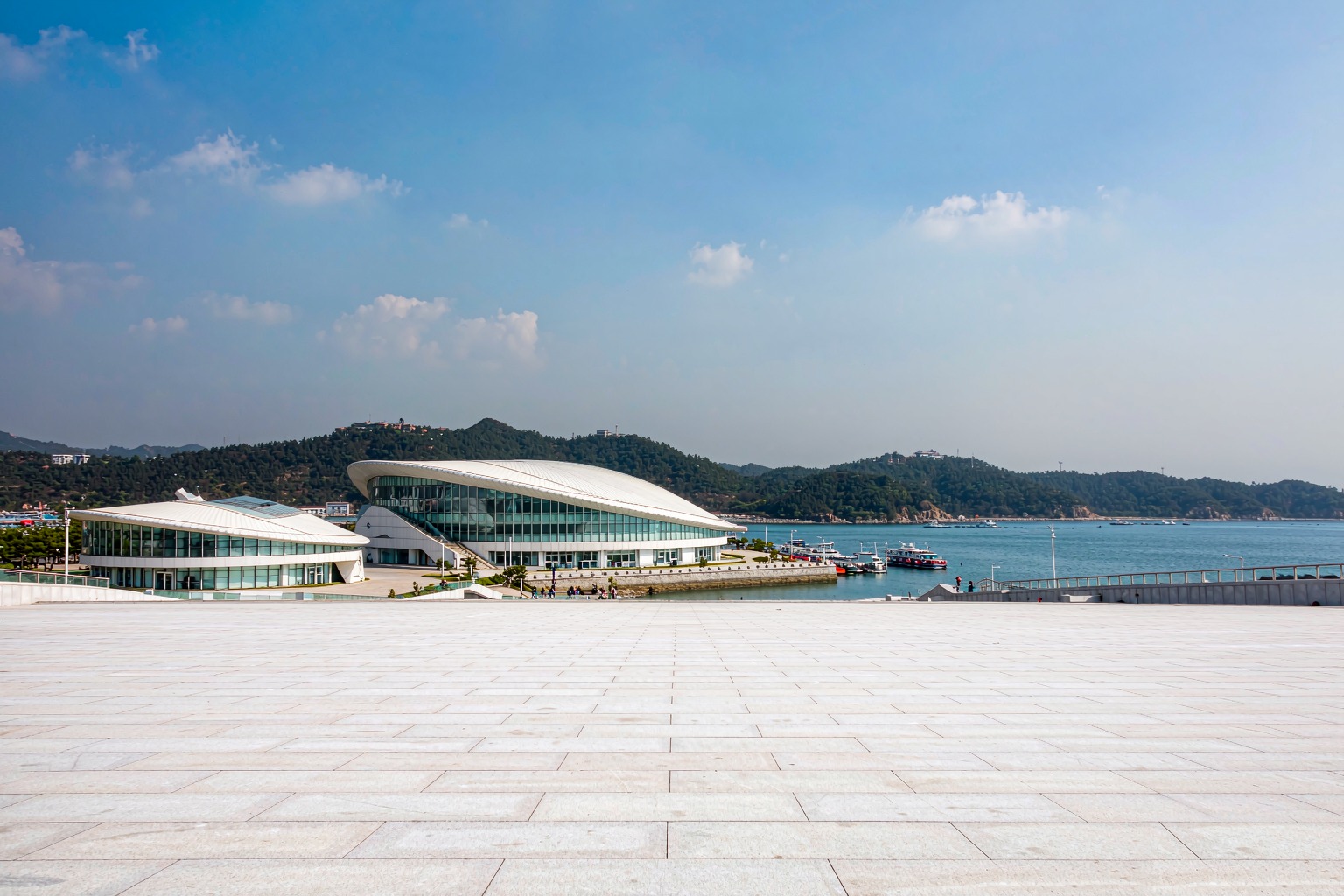 The entrance plaza and exhibition halls of Laohutan Ocean Park under a wide blue sky.