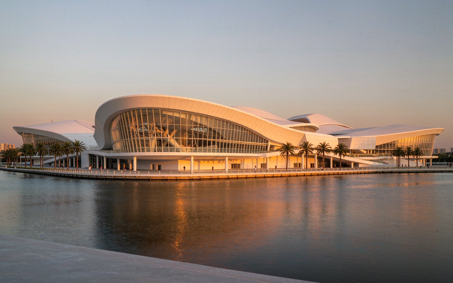 Long white museum building curving along a river promenade