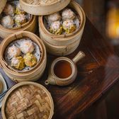 Bamboo steamers of har gow and siu mai dim sum beside a pot of tea