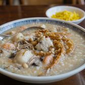 A bowl of sampan congee topped with fish, shrimp and peanuts