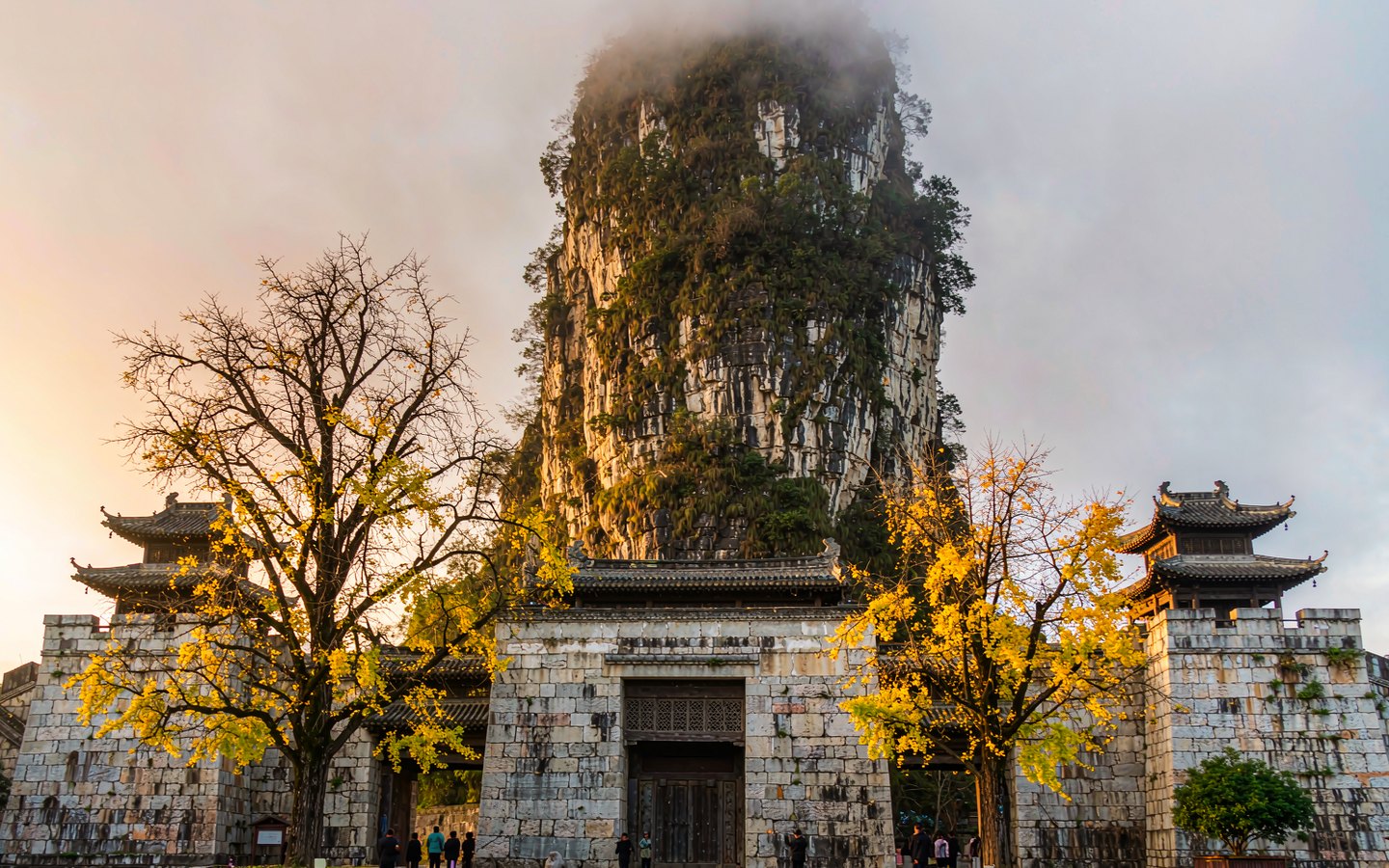 Lone limestone pinnacle rising behind Ming palace walls and old trees