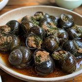 Dark river-snail shells packed with minced pork, in a bowl of sauce
