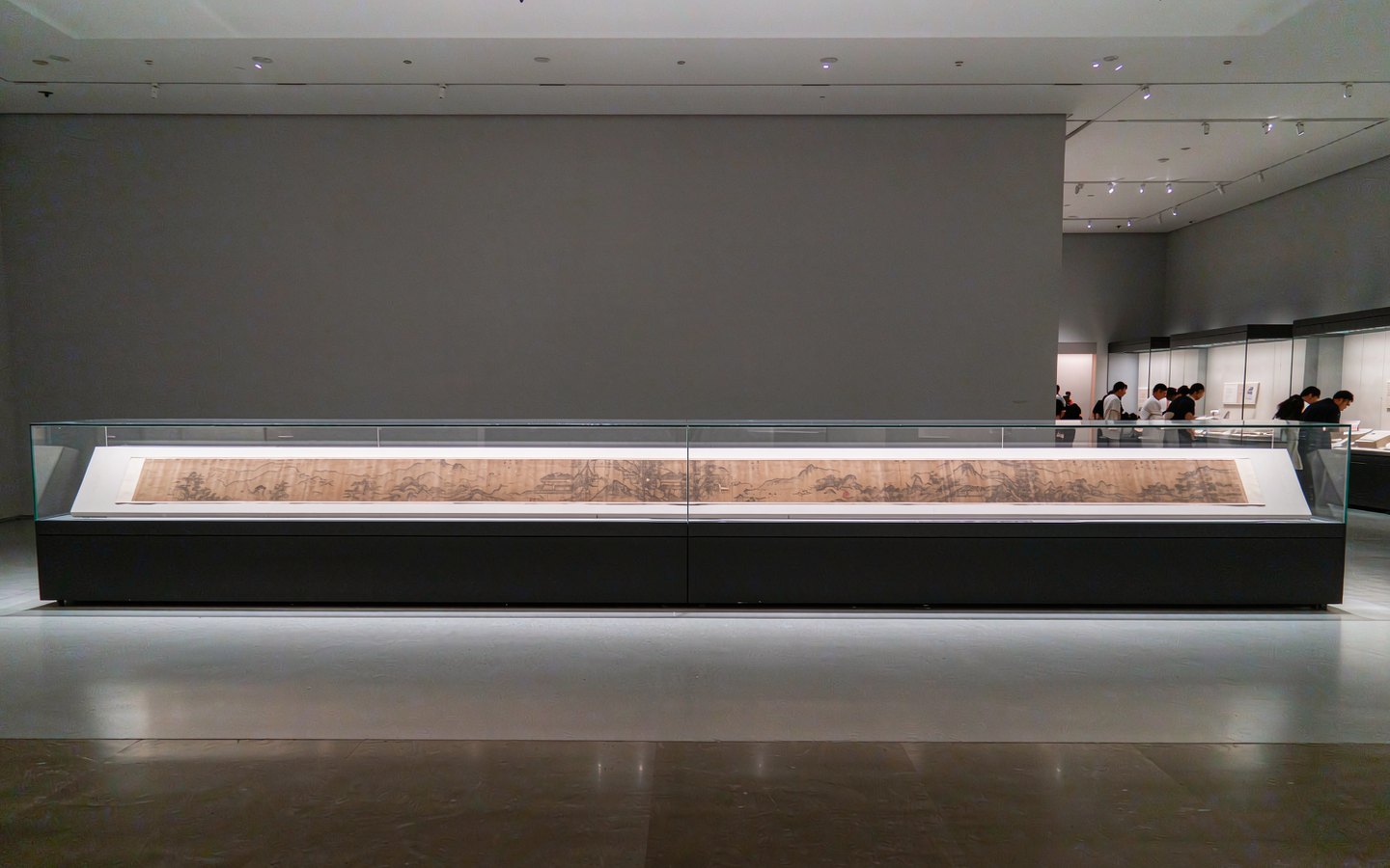 Ancient handscroll painting in a long glass case in a dim gallery