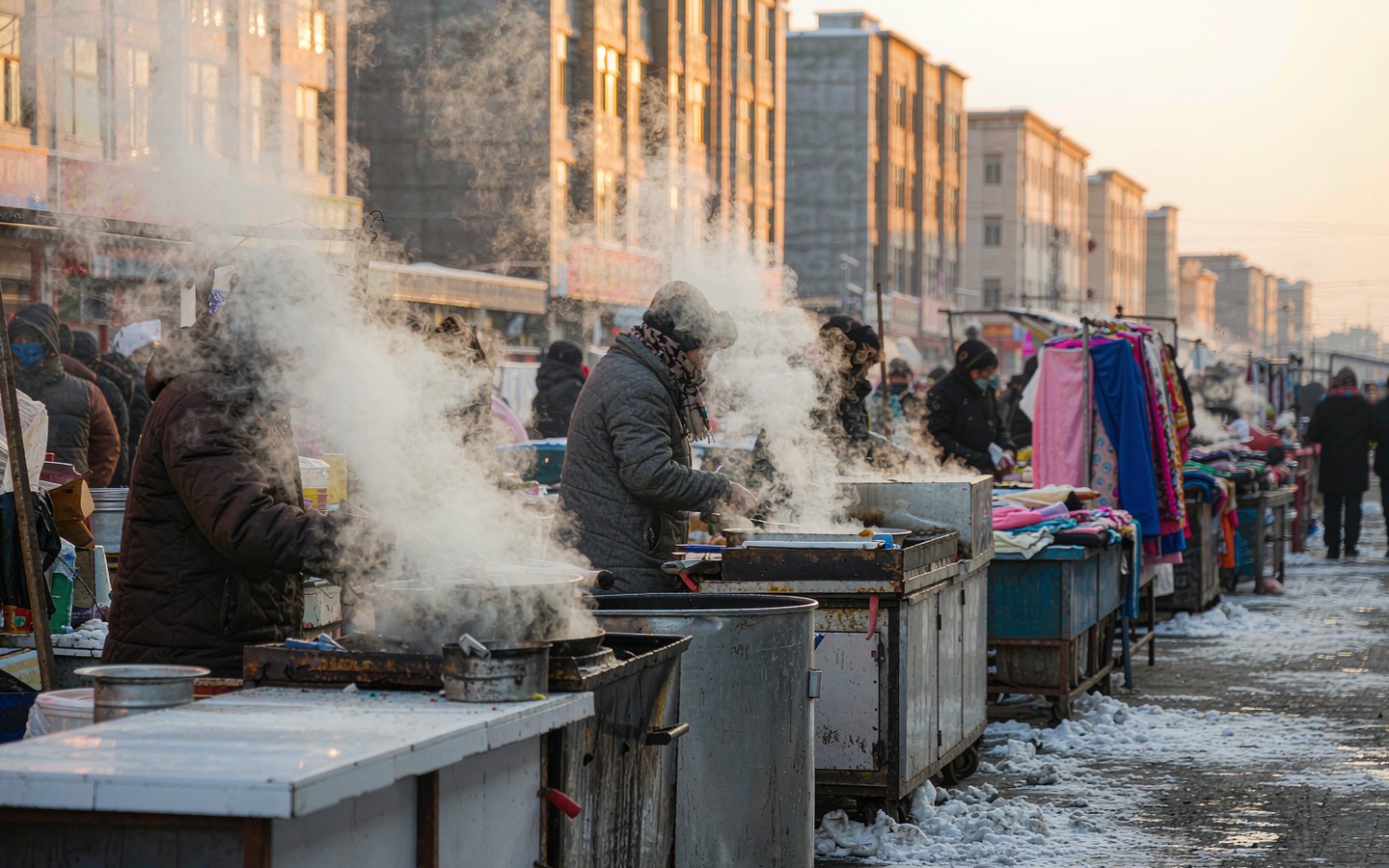Steam rising from breakfast stalls at a snowy dawn market