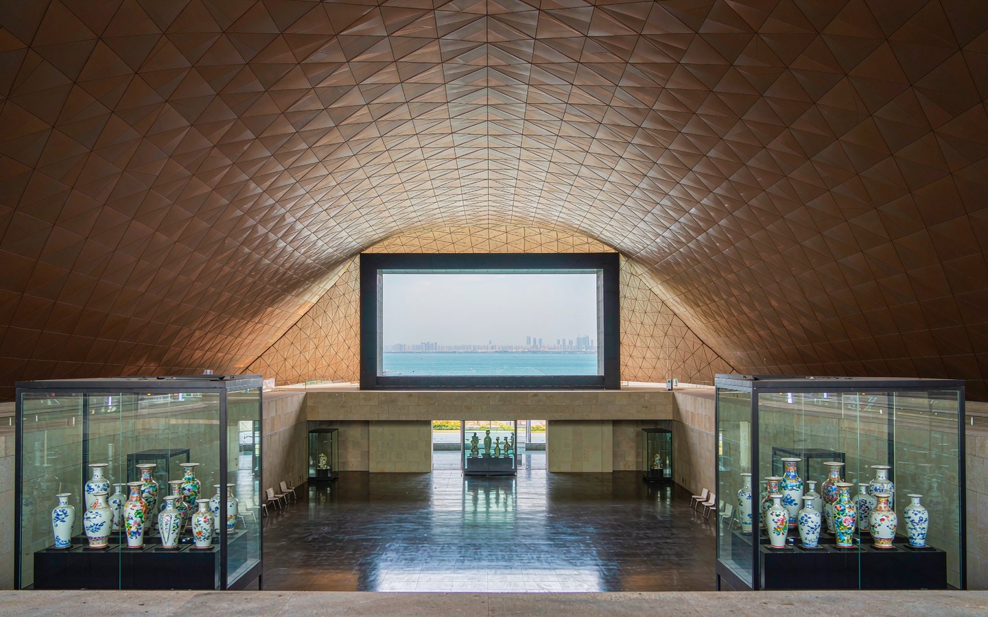 Modern bronze-toned museum atrium with imperial ceramics on display