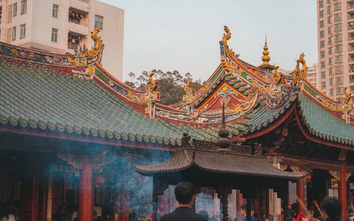 Worshippers with incense before a red-and-gold temple hall