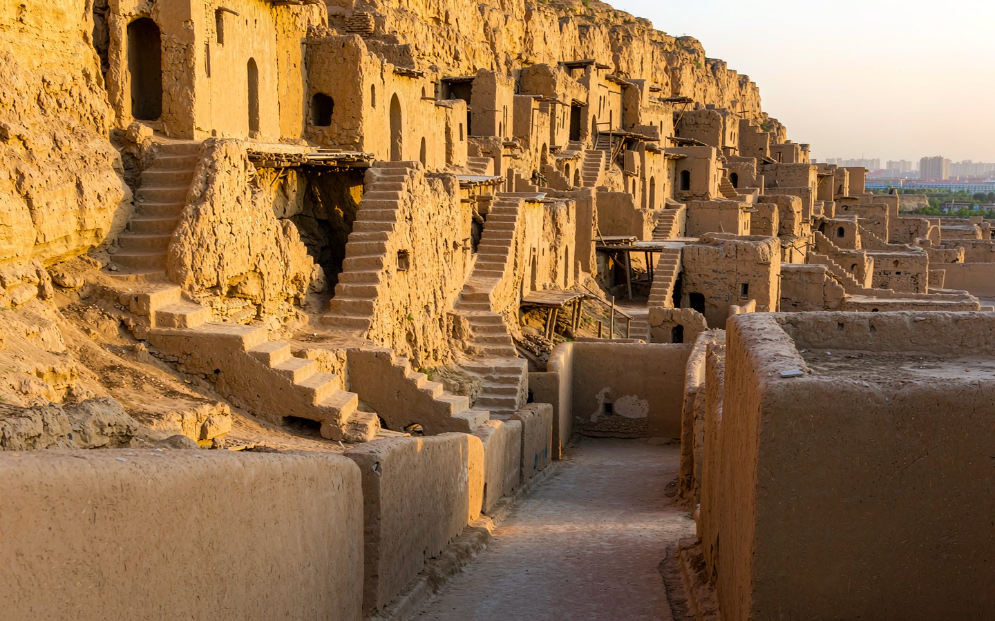Mud-brick houses stacked on a loess cliff above the modern city