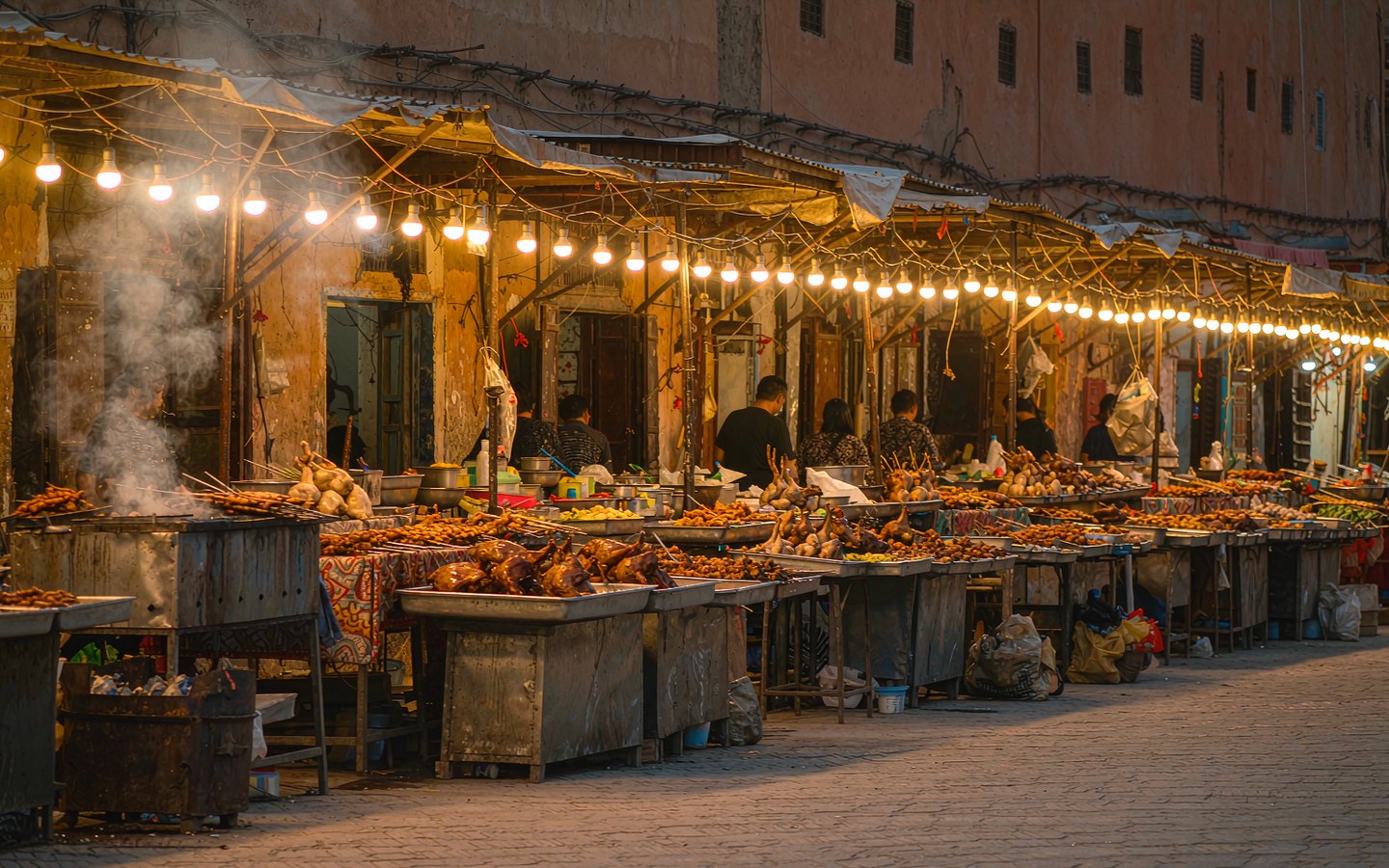 Smoky night-market grills under strings of lights in the old town