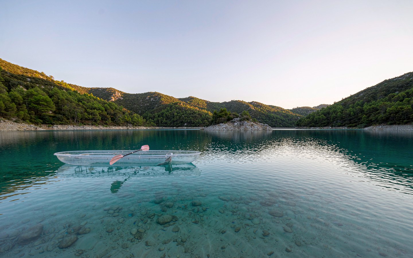 Clear boat over white sand in a turquoise mountain lake
