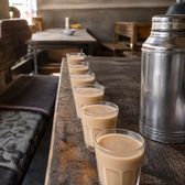 Glasses of milky sweet tea along a tea-house table beside a steel thermos