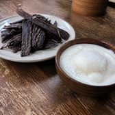 Strips of air-dried yak meat beside a wooden bowl of thick plain yoghurt