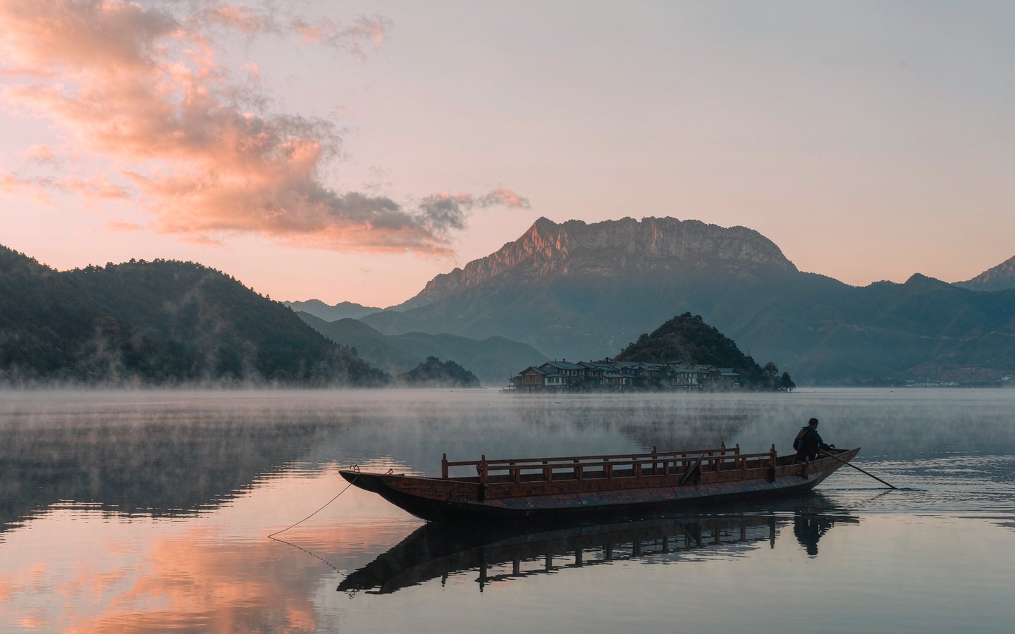 Wooden canoe on a mirror-calm alpine lake at sunrise