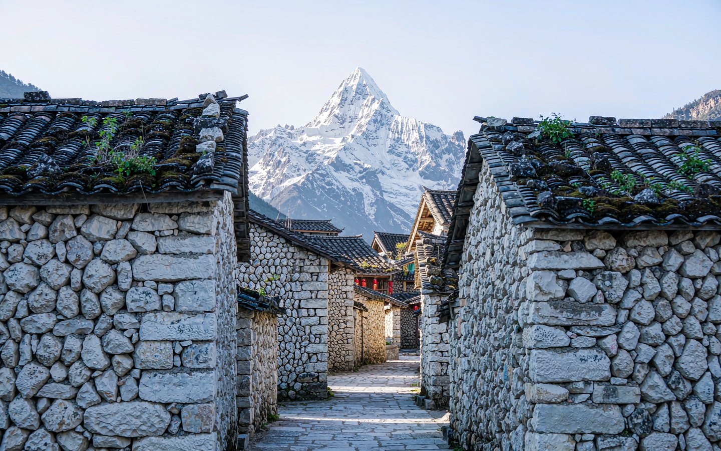 Stone cottages beneath a snow peak along a glacier-stone lane