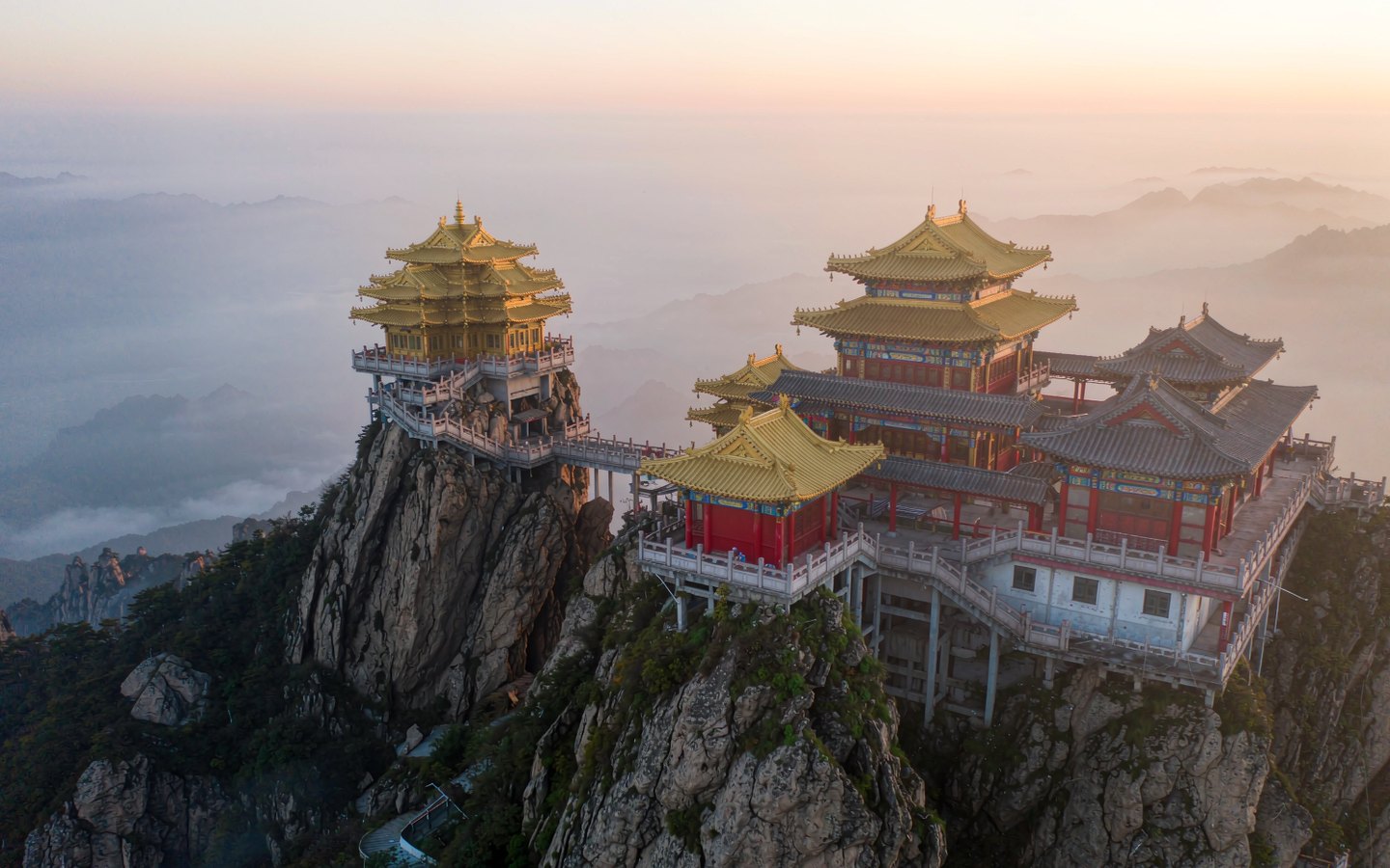 Golden Taoist temples on a cliff above a rolling sea of clouds