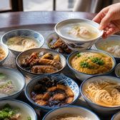 A round table crowded with small bowls of clear soups and stewed dishes