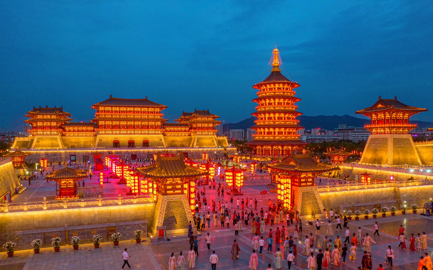 Visitors in Tang hanfu beneath lantern-lit towers at night