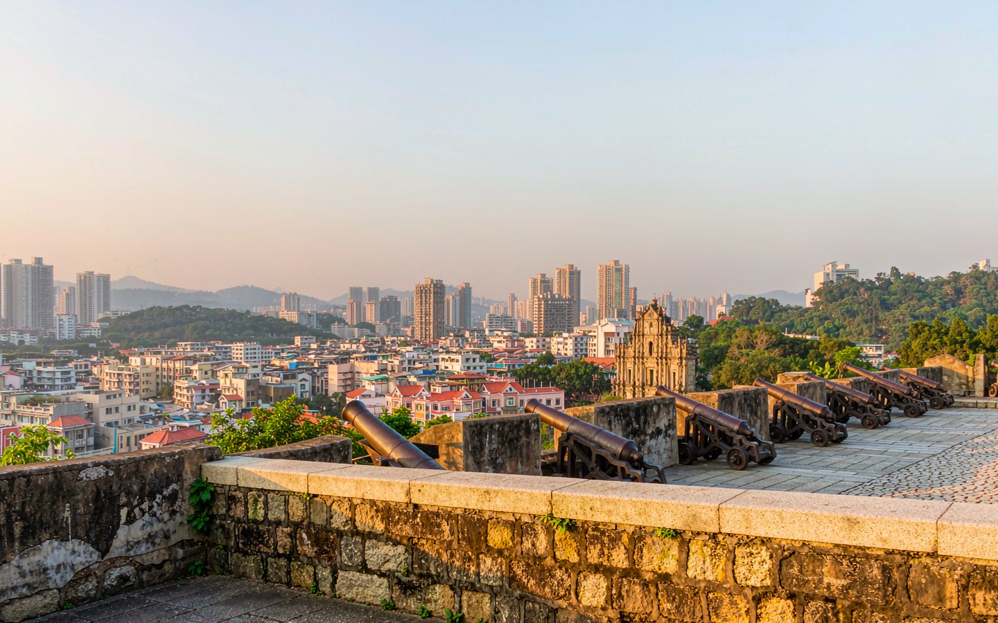 Old cannons on a fortress terrace overlooking dense city rooftops