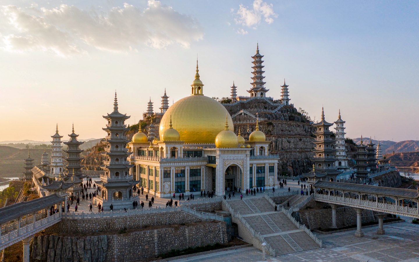 Golden domed palace rising from a quarry cliff on a forested hill