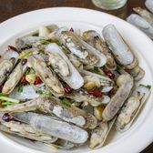 Spicy stir-fried clams with dried red chillies, garlic and spring onion on a white plate