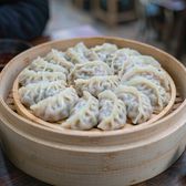 Plump steamed mackerel dumplings on a bamboo steamer with vinegar and ginger
