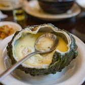 Smooth pale yellow egg custard steamed inside a halved sea-urchin shell, with a small spoon
