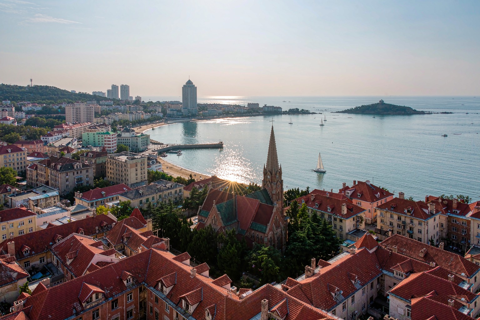 Aerial three-quarter view of Qingdao's red-tile old town meeting the sea