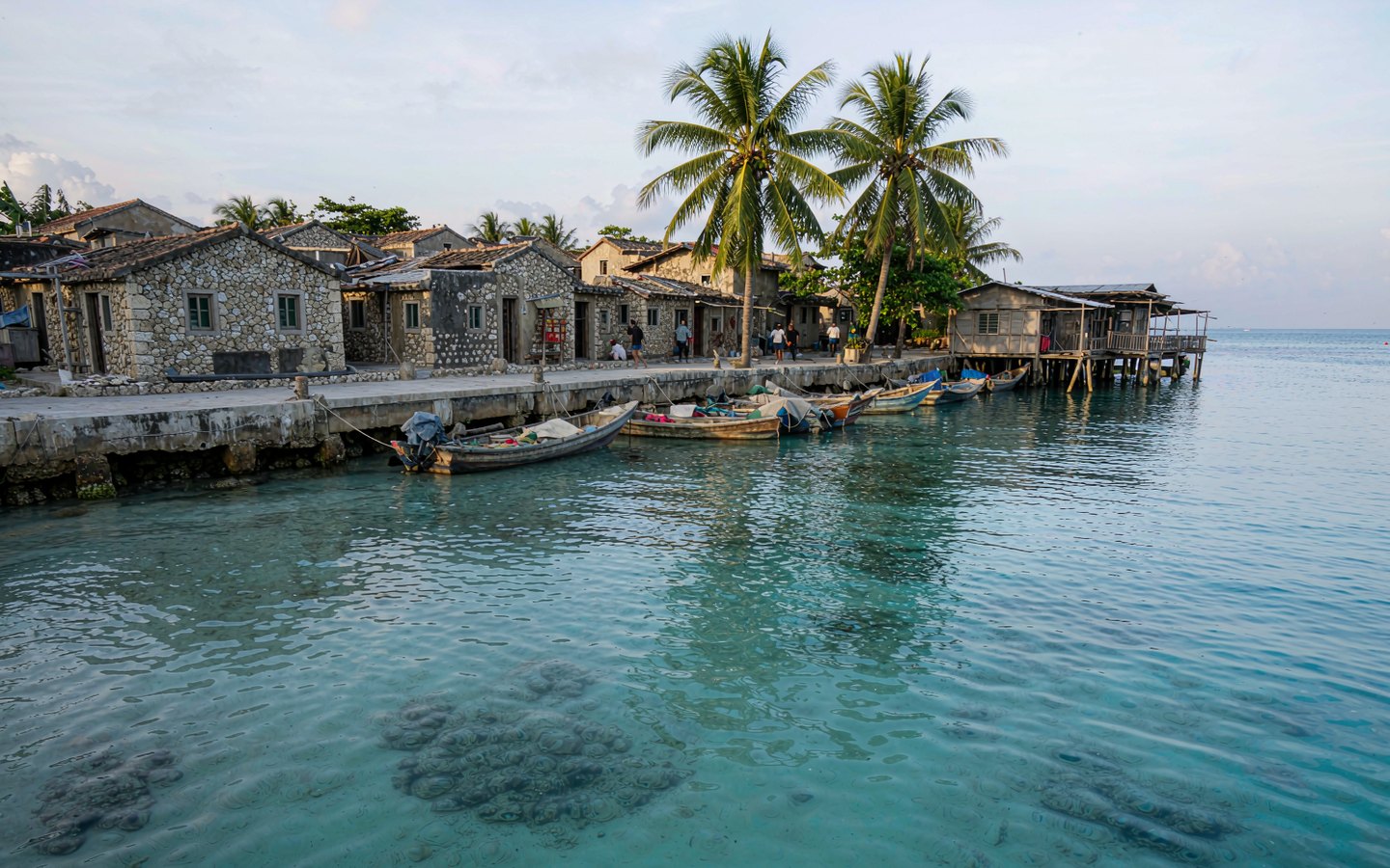 Fishing boats at a village pier with clear turquoise shallows