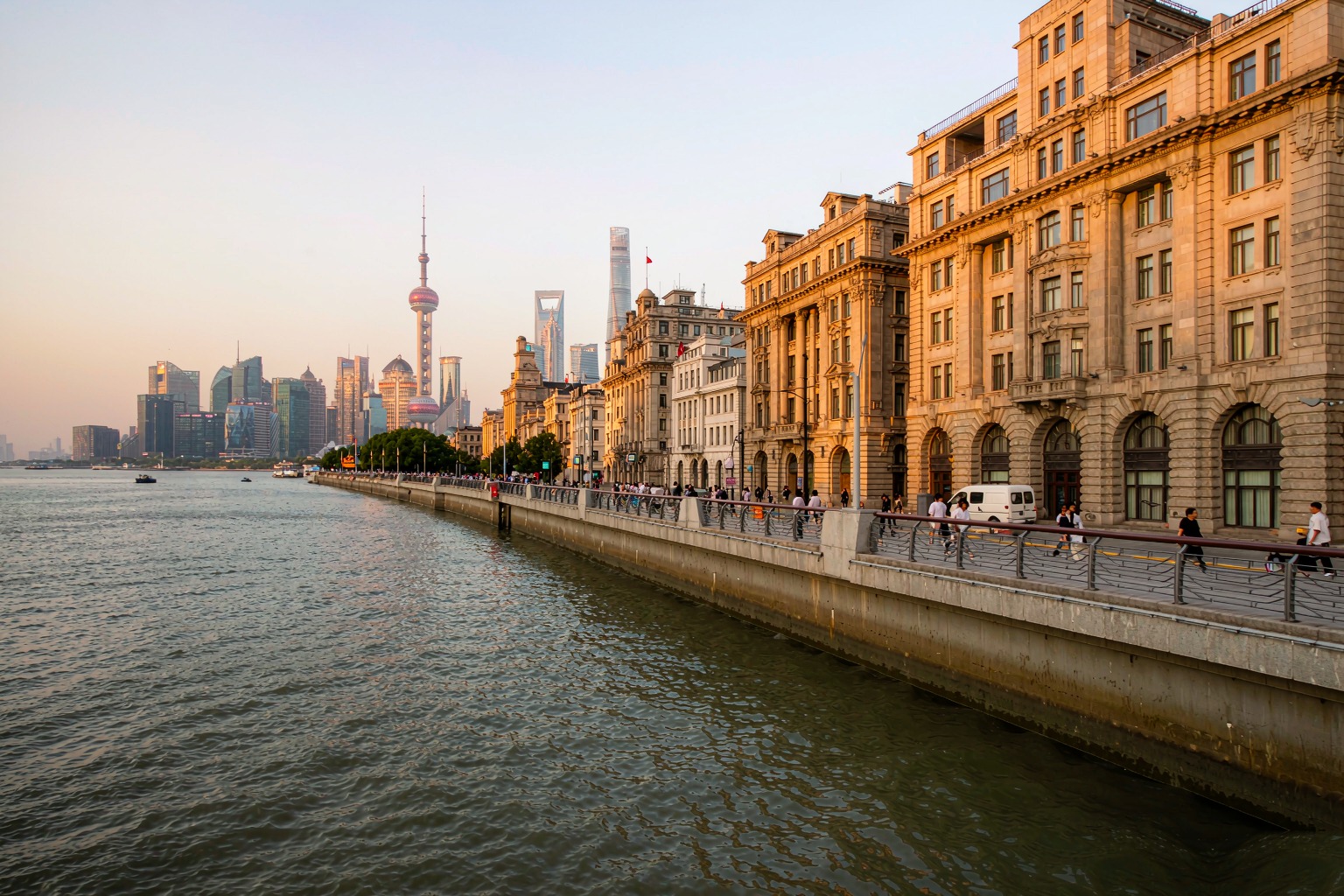 Historic art-deco buildings along the Bund promenade at golden hour, Pudong skyline across the Huangpu River, Shanghai