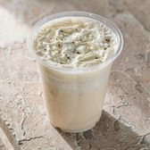 A cup of cheese-foam jasmine milk tea with a cream cheese layer on a stone cafe counter
