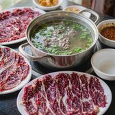 A pot of clear beef broth ringed by plates of thinly sliced raw beef