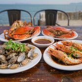 Plates of steamed prawns, crab and clams on a seaside restaurant table