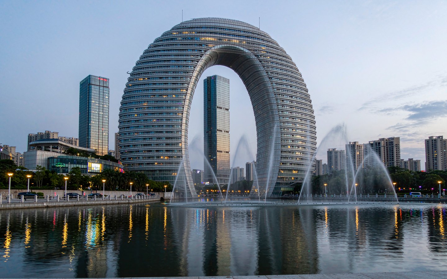 Gate-shaped skyscraper and skyline across a wide lake at dusk