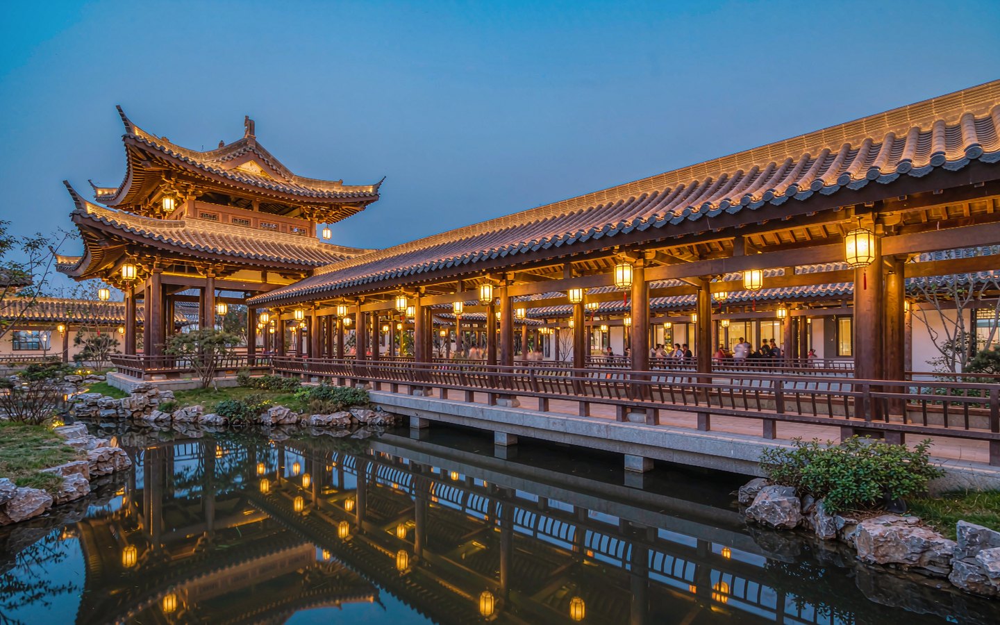 Lantern-lit garden pavilion with musicians beside a moonlit pond