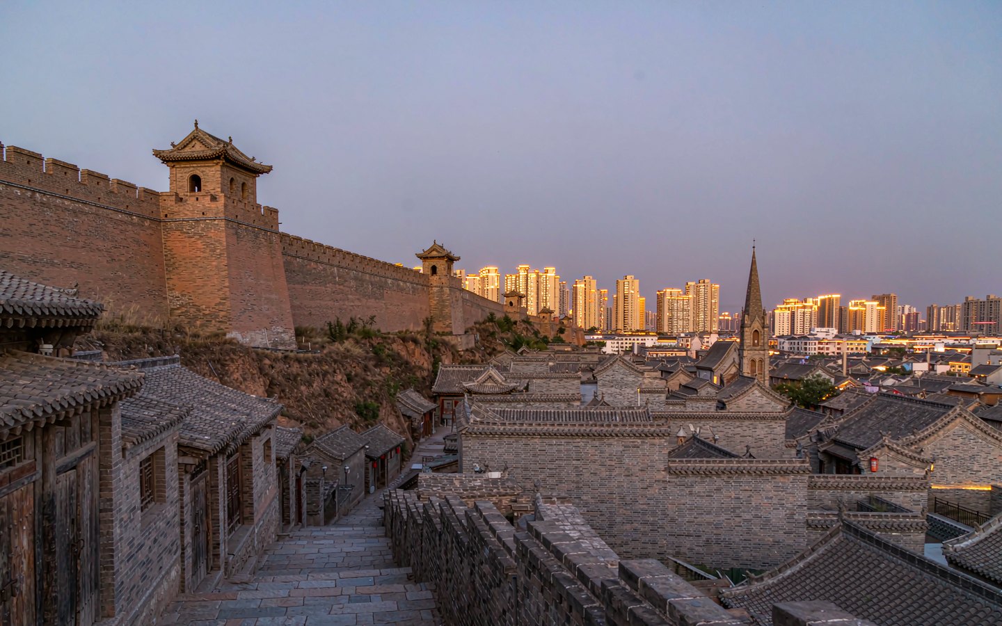 Restored city wall on a hill above old lanes and a church spire