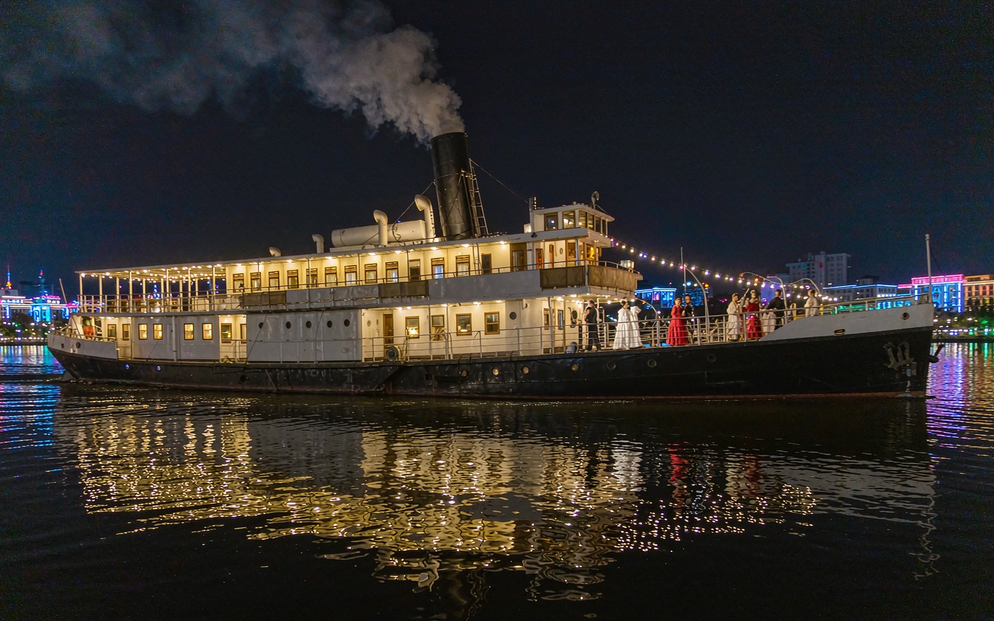 Retro steamship glowing at night with costumed actors on deck