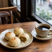 Small flaky mung-bean pies on a plate beside a cup of black coffee