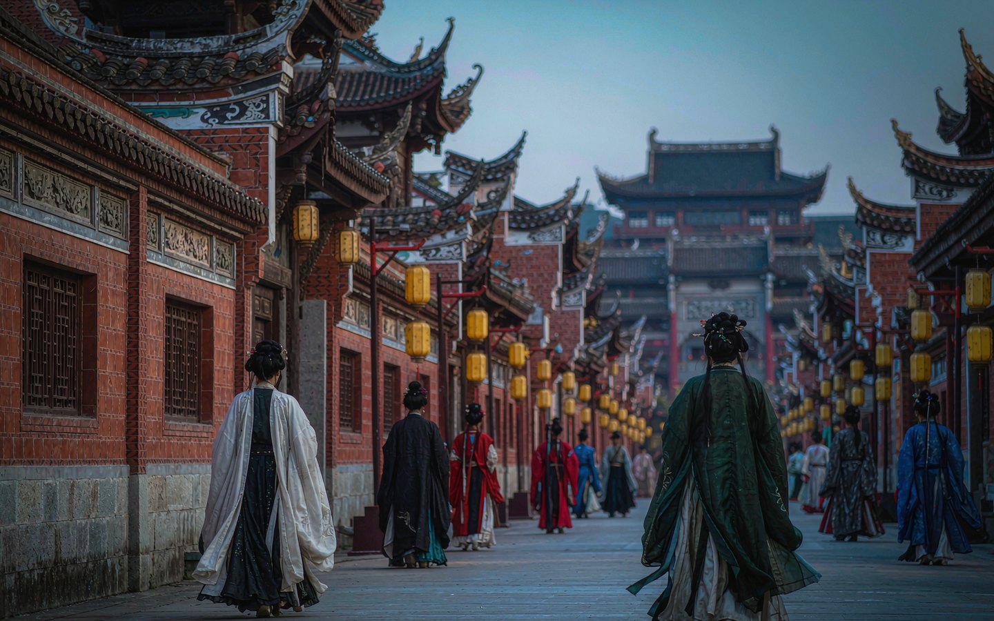Visitors in flowing hanfu crossing a lantern-lit heritage street