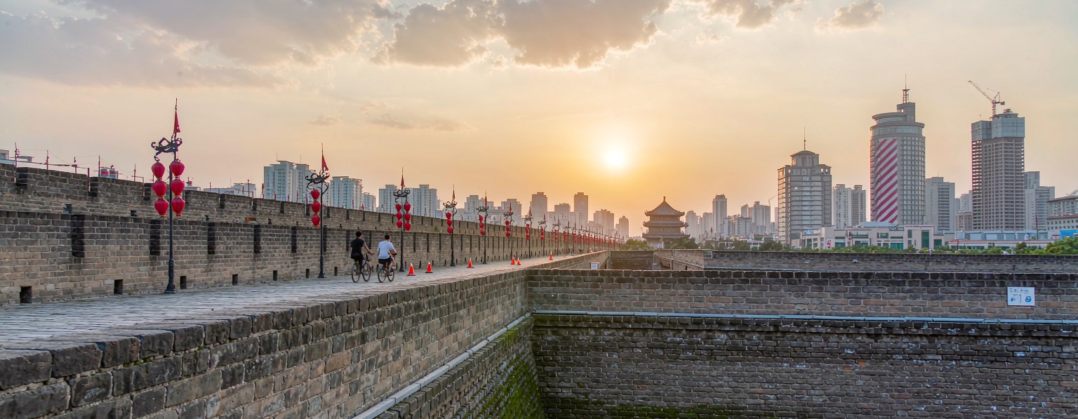 Cyclists on top of the Xian city wall at sunset, red lanterns and the skyline behind