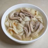 Rings of braised pork intestine and torn flatbread in a clear broth