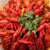 A white platter piled with bright red whole crayfish in chilli oil, topped with a handful of coriander and a green chilli.