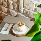 A creamy dessert jar with spoon on table against a rustic brick wall, perfect for cafe ambiance.